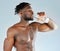 Its just what I need right now. Studio shot of a muscular young man drinking a glass of water.