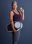 Its a lifestyle. Studio portrait of an attractive mature woman holding an apple and a weightscale against a blue