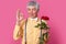 Its perfect. Photo of attractive mature man with grey hair, wears elegant yellow shirt, bowtie and suspenders, holds bouquet of