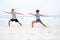 Its the perfect setting to find some calm. a young man and woman practising yoga together at the beach.