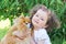 Ittle beautiful girl with pet on nature. happy child huging a dog. Female playing with Pomeranian Spitz outdoors. the best friends