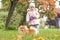 Ittle girl walking with dog on a leash in the autumn park. child playing with pomeranian spitz