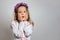 Ittle girl in white dress and purple wreath on gray isolated background