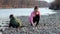 Ivano-Frankivsk, 29 May 2020: Young woman with her son collects plastic garbage in a garbage bag on the river. Empty