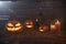 Jack-O-Lantern Halloween pumpkins on rough wooden planks with candles