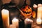 jack o lantern pumpkin with candles, bowl, witch broom and bats, ghosts on background in dark spooky room. Happy Halloween