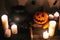 jack o lantern pumpkin with candles, bowl, witch broom and bats, ghosts on background in dark spooky room. Happy Halloween