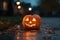 Jack-o-lantern pumpkin on rainy street at dusk