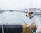 Jack Russell Terrier dog sitting with a fishing rod near the harbor.