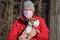 Jack Russell terrier wearing white cotton mouth mask, owner in red jacket with virus face mask in background. Pets are not