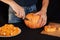 Jack`s Halloween pumpkin. Hands of a man with a knife cutting orange pumpkin