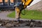 Jackhammer excavator breaks curbs along the road