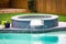 A jacuzzi hot tub next to a large freeform swimming pool with a waterfall water feature running