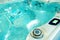 Jacuzzi with turquoise clear water. A fragment of a swimming pool with a control panel and massage heads for wellness treatments.