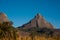 A jagged and rocky mountain peak rising steeply from the grassy plains