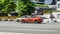 Jaguar F-Type P450 car is driving on the street on high speed. Orange premium sports car in motion