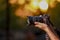 Jalgaon, Maharashtra / India - May 4, 2020 : Closeup of a black camera holding by Photographer`s hand with sunset background