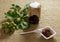 Jam jar nuts on textured burlap with leaves, fruit, white ceramic plate and spoon