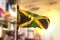 Jamaica Flag Against City Blurred Background At Sunrise Backlight