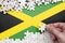 Jamaica flag is depicted on a table on which the human hand folds a puzzle of white color