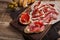 Jamon Iberico with white bread, olives on toothpicks and fruit on a wooden background. Top view