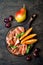 Jamon serrano or prosciutto with melon and fruits over rustic wooden background. Italian or spanish antipasti, appetizer board.