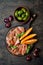 Jamon serrano or prosciutto with melon and olives over rustic wooden background. Italian or spanish antipasti