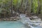 Jangle landscape with flowing turquoise water of Erawan cascade waterfall