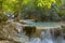 Jangle landscape with flowing turquoise water of Erawan cascade waterfall