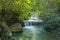 Jangle landscape with flowing turquoise water of Erawan cascade waterfall