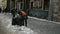 Janitor cleans garbage from a dumpster in a street.