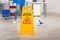 Janitor Mopping Floor By Wet Caution Sign In Office