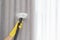 Janitor removing dust from curtain with steam cleaner