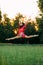 Japanese ballerina jumps and performs gymnastic twine on lawn