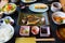 Japanese breakfast dishes including cooked white rice, grilled fish, fried egg, miso soup,