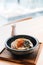 Japanese Chashu Don: Steam Rice topping with Roasted Pork Belly, Yolk, Dried Seaweed and Saffron. Served in black ceramic bowl.