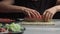 Japanese chef prepares sushi rolls with salmon and avocado. Cook hands making Japanese sushi roll on the bamboo mat