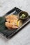 Japanese chicken grilled with sea salt served with sliced lemon and wasabi in stone rectangle plate on washi Japanese paper