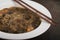 Japanese cuisine, soup with chashu pork, chives, sprouts, noodles and seaweed on the table under the sunlight. Old black rustic ba