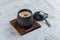 Japanese custard pudding torched caramel on top served in black ceramic cup on wooden plate with lid and spoon on washi.