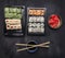 Japanese fast food, sushi set with various ingredients in plastic containers on dark rustic background, top view