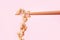 Japanese fermented natto beans on wooden chopsticks on pink background.