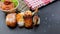 Japanese food composition. Various kinds of sushi placed on black board. Spicy salmon salad.