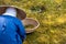 Japanese gardener works on green grass pick up scraps of wood and dry grass to basket on garden floor, wearing blue shirt, big bam