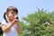 Japanese girl blowing dandelion seeds under the blue sky