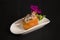 Japanese Gunkan sushi with fresh salmon and Tobico caviar served on white plate decorated with fresh flower on dark background