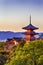 Japanese Heritage. Renowned Kiyomizu-dera Temple Pagoda Against Kyoto Skyline  and Traditional Red Maple Trees in Background in