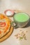 Japanese iced Matcha latte tea with pizza margherita and pistachios on wooden table.