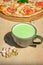 Japanese iced Matcha latte tea with pizza margherita and pistachios on wooden table.