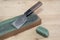 Japanese leather craft knife on a leather knife strop with green polishing compound on a wooden surface